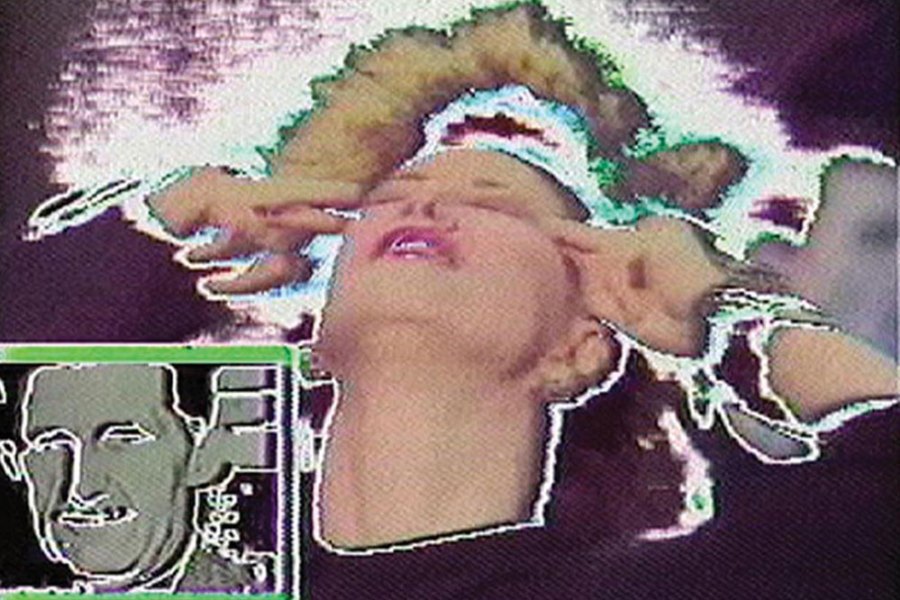 film still of glitching screen with a woman pressing her fingers to her temples