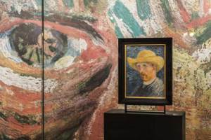 Vincent Van Gogh’s 'Self-Portrait with Straw Hat' (1887) against an enlarged detail of the eyes from 'Self-Portrait with Grey Felt Hat (1887) on the ground floor of the Van Gogh Museum