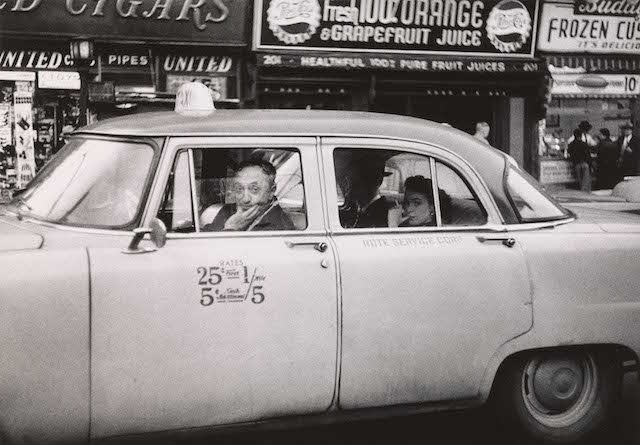 Taxicab driver at the wheel with two passengers, N.Y.C