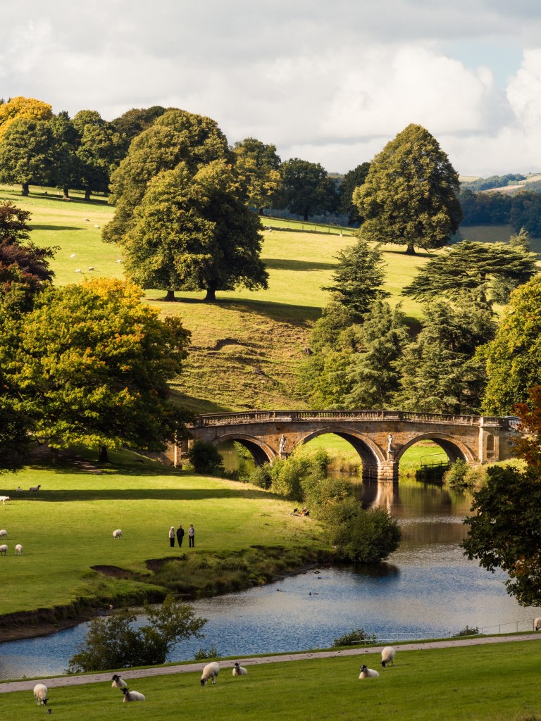 View over the parkland at Chatsworth House, and the River Derwent and stone bridge.