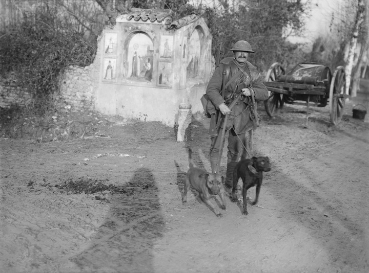 Soldier from the Royal Engineers with two messenger dogs and a roadside shrine (December 1917), Ernest Brooks. Courtesy: Imperial War Museum