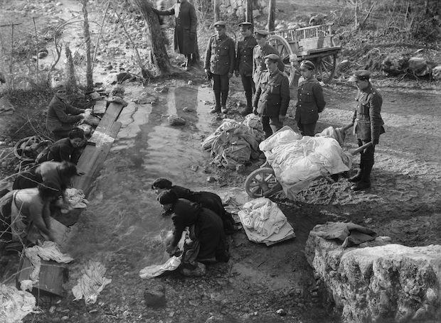 Men of the Royal Engineers watch as their clothes are washed in a stream by Italian peasant women (November-December 1917), Ernest Brooks. Courtesy: Imperial War Museum