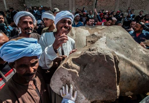 Egyptian workers pose next to an excavated statue, recently discovered by a team of German-Egyptian archeologists, in Cairo's Mattarya district on March 13, 2017.