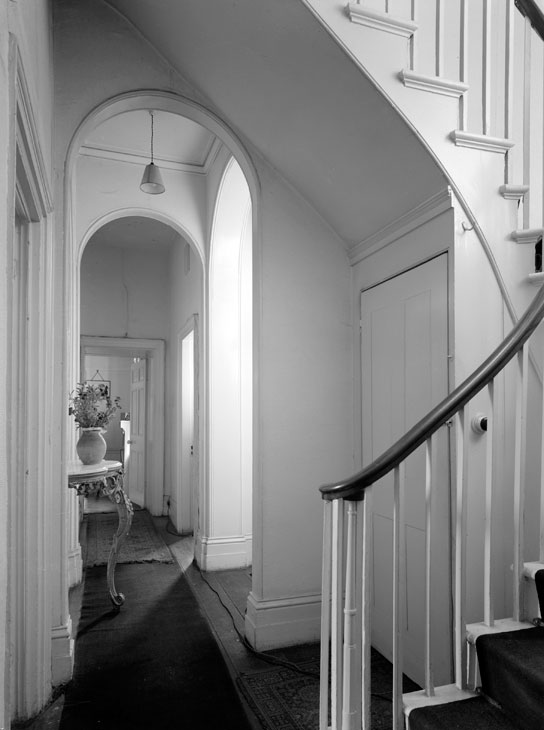 The interior of Sandycombe Lodge before restoration, showing the curved staircase and arched corridor. © Country Life