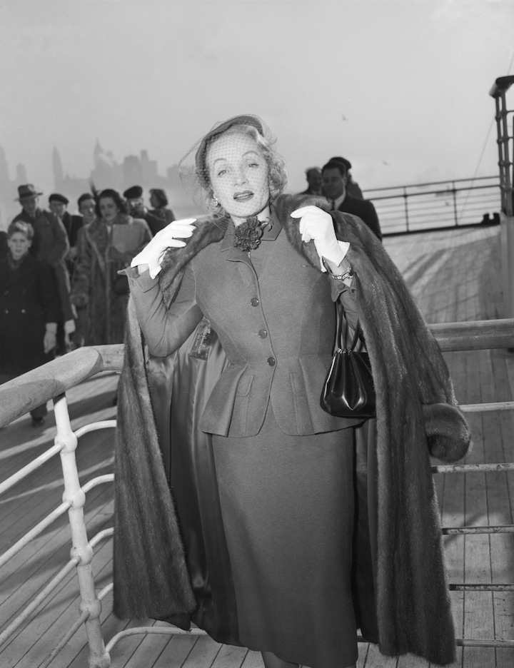 Photograph of Marlene Dietrich wearing a day suit by Christian Dior on-board the Queen Elizabeth arriving in New York, 21 December 1950. © Getty Images