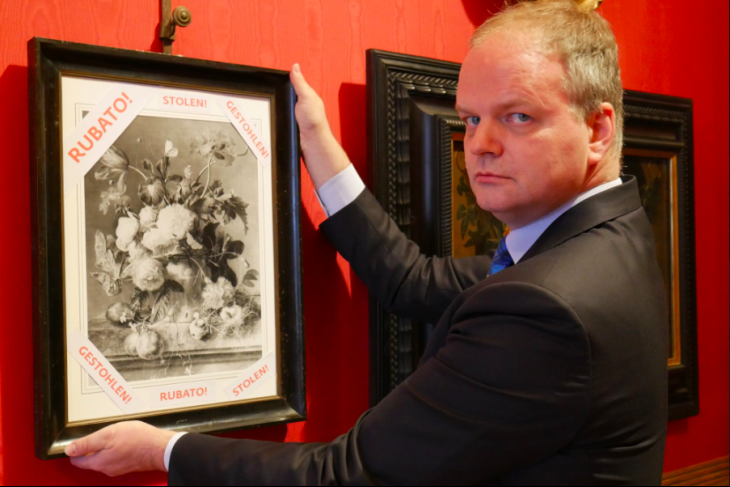 Uffizi director Eike Schmidt with a framed photograph of 'Vase of Flowers' and the word 'stolen' in Italian, English and German. Photo: @UffiziGalleries via Twitter