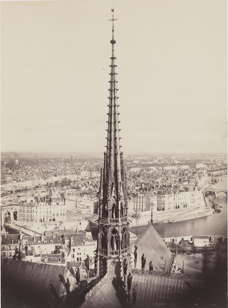 View of spire, roof with statuary, and cityscape beyond
