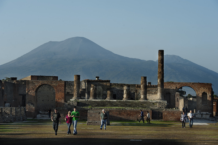 Tourists visit the archaeological site of Pompeii, with Vesuvius behind them