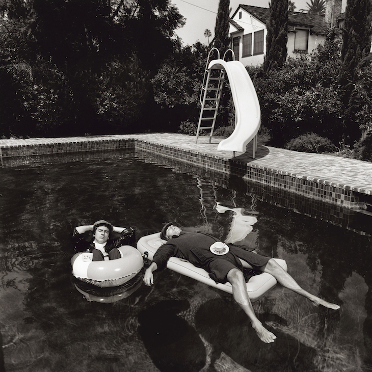 Peter Cook and Dudley Moore relaxing in a Beverly Hills swimming pool while in costume as the characters Pete and Dud, 1975.