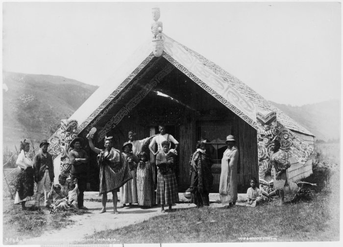 A Maori group in front of Hinemihi at Te Wairoa, photographed by the Burton Brothers between 1880–86 (before the volcanic eruption of 10 June 1886).