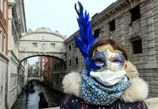 A tourist in Venice on 24 February 2020, wearing a protective face-mask and a Carnival mask.