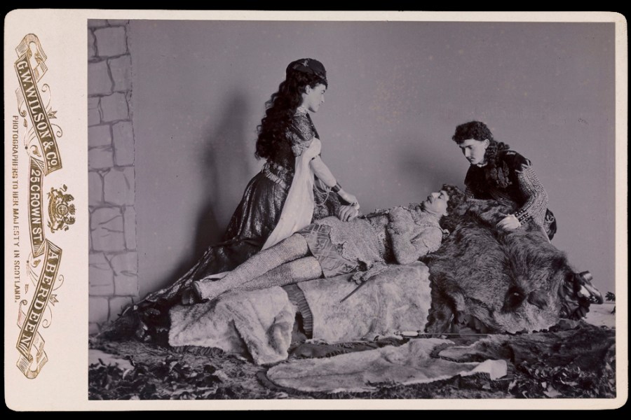 Photograph taken at Balmoral in 1893/94 by Charles Albert Wilson. Ethel Cadogan, Lord William Cecil and Dr Alexander Profeit re-enact a scene from Ivanhoe by Sir Walter Scott in which Rebecca and a page kneel over Ivanhoe. Royal Collection Trust/© HM Queen Elizabeth II 2020