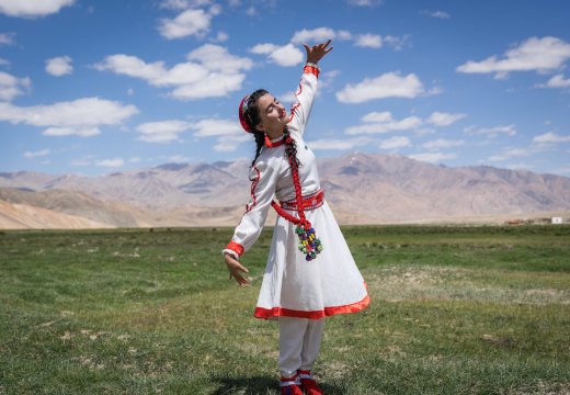 A girl in traditional Tajik dress dances at the opening of a new tourism centre in Bulunkul, Tajikistan (2019), Christopher Wilton-Steer.