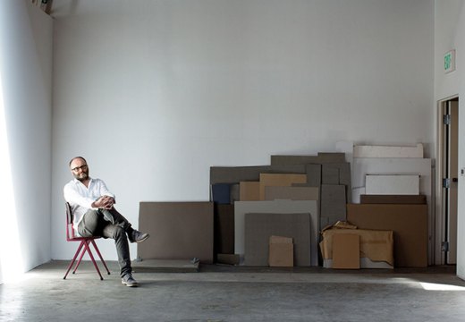 portrait of a man sitting on a chair in a warehouse space