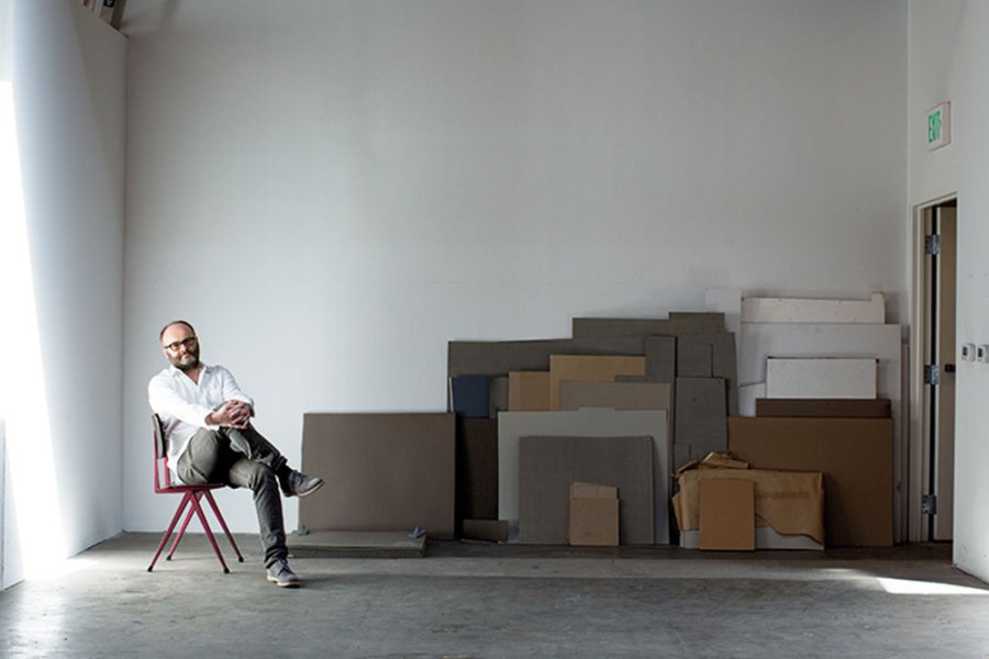 portrait of a man sitting on a chair in a warehouse space