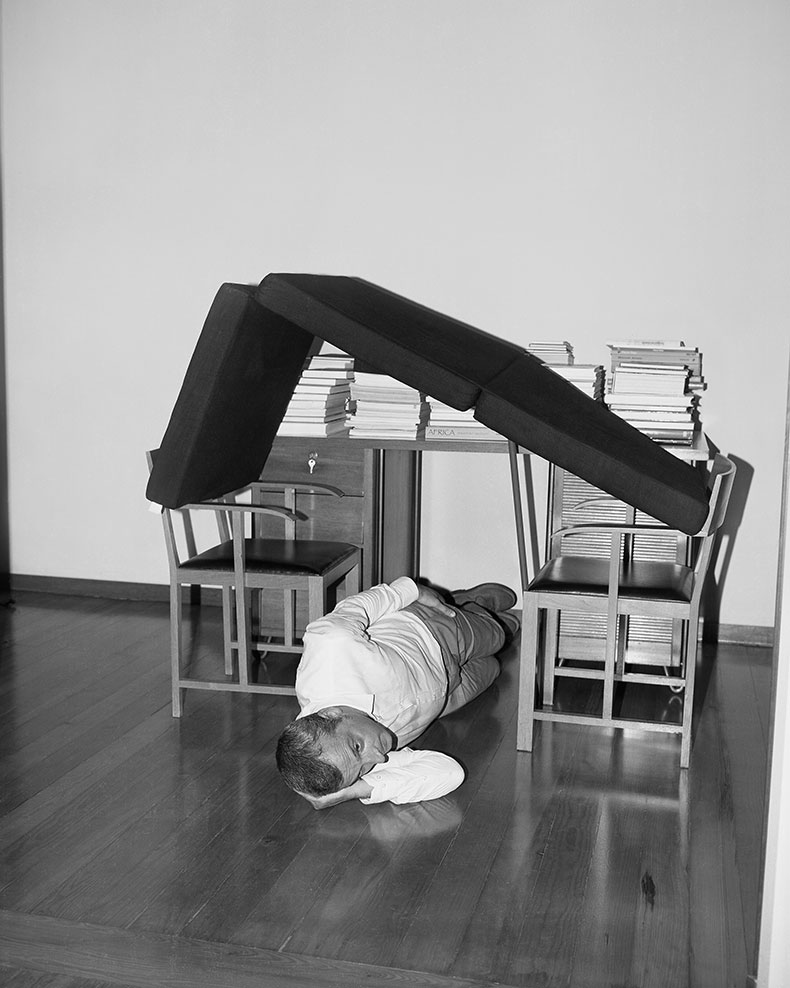 photograph of a man lying underneath furniture