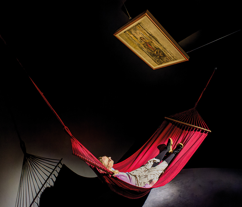 woman lying in a hammock looking at an artwork