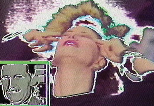 film still of glitching screen with a woman pressing her fingers to her temples