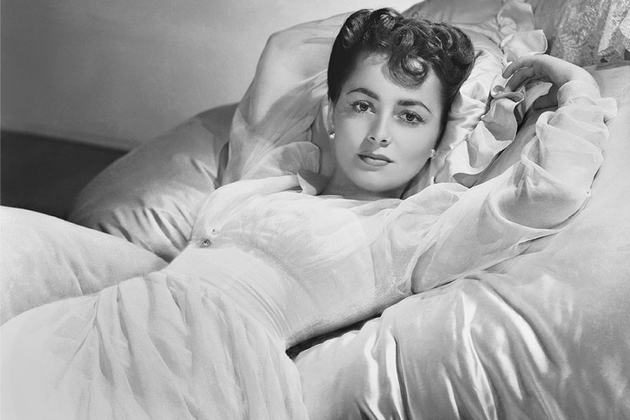 Actress Olivia de Havilland lying on a bed